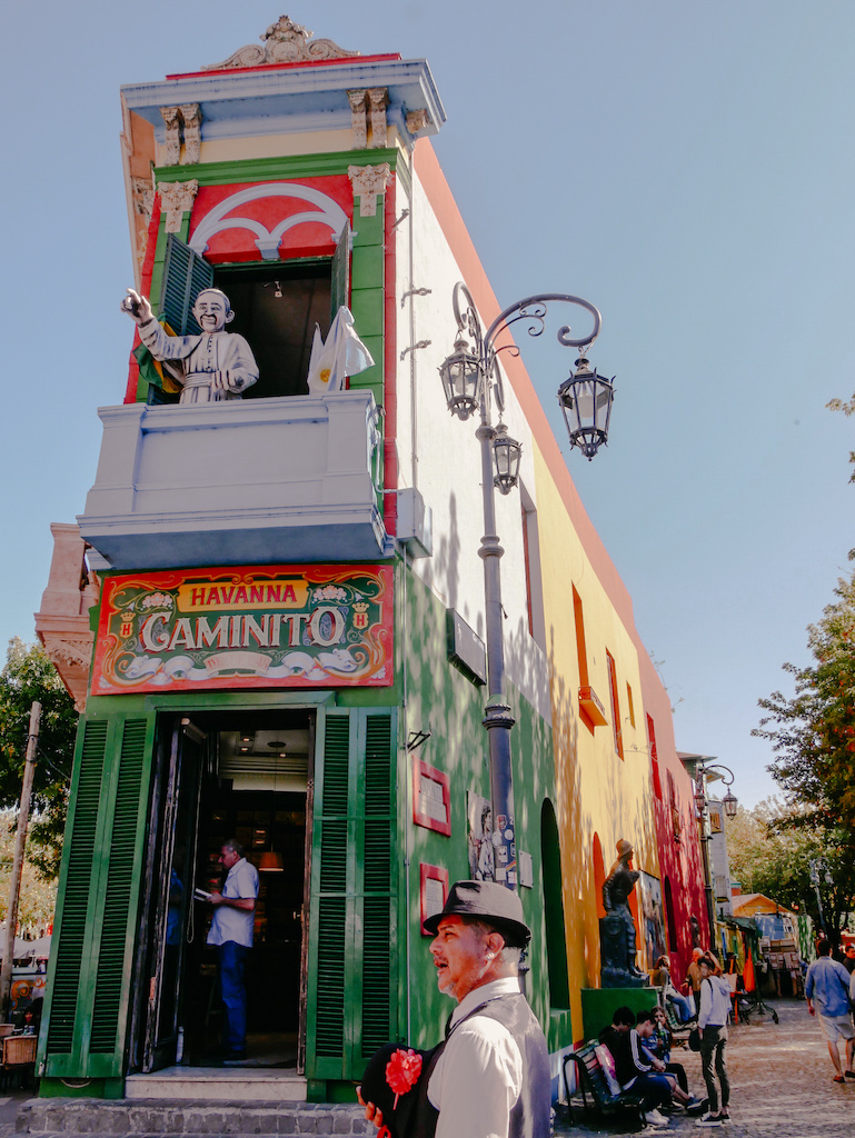 Buntes Haus in La Boca, Buenos Aires, Argentinien mit einem Mann mit Rose davor.