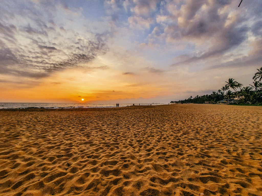 Langer, breiter Sandstrand bei Sonnenuntergang